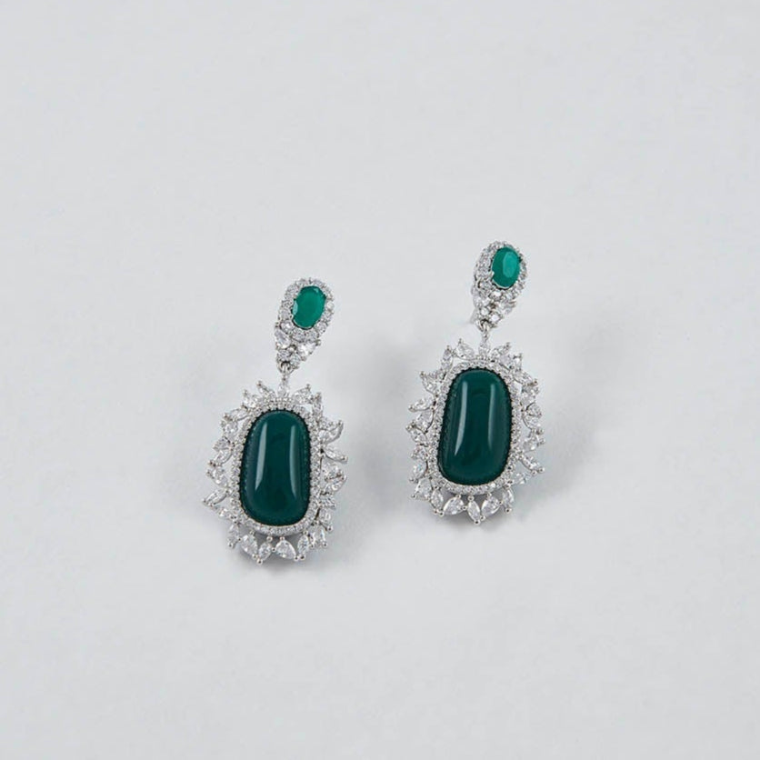Pair of earrings with green gemstones on a light gray background