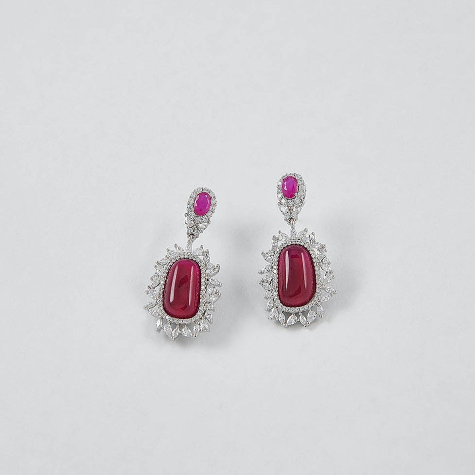 Pair of earrings with red gemstones on a light gray background