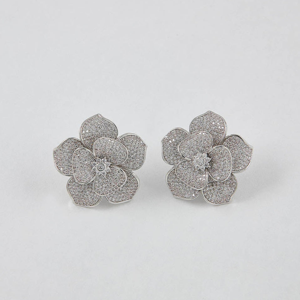 Pair of silver flower-shaped earrings on a white background