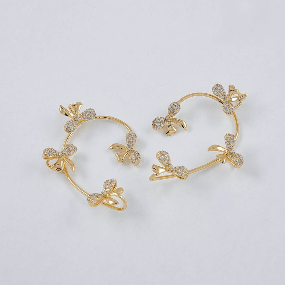 Gold hoop earrings with floral designs on a light gray background