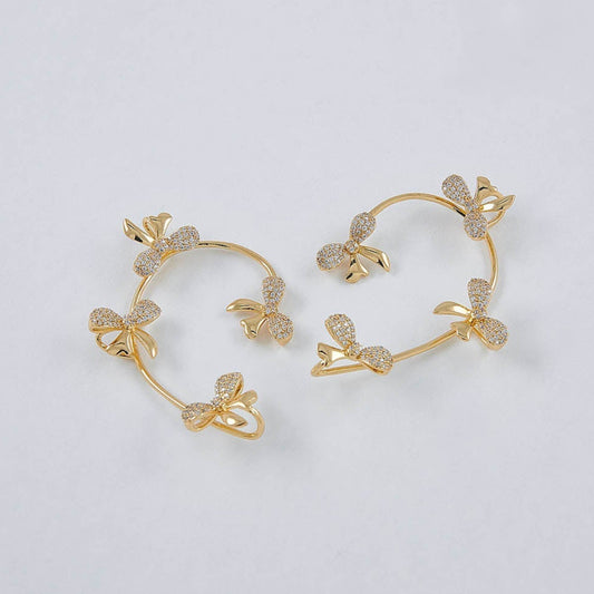 Gold hoop earrings with floral designs on a light gray background