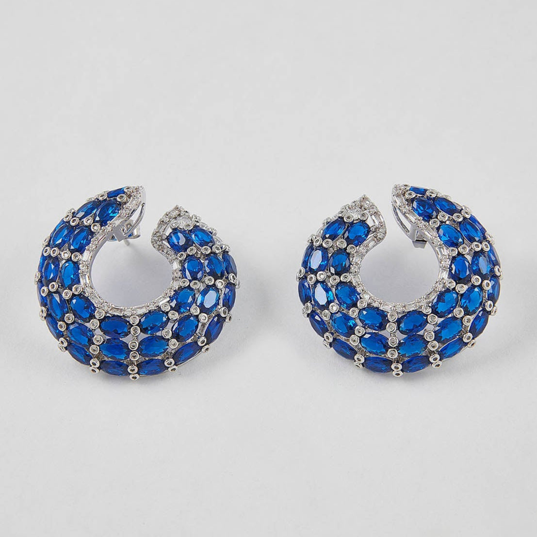 Pair of hoop earrings with blue gemstones on a light gray background