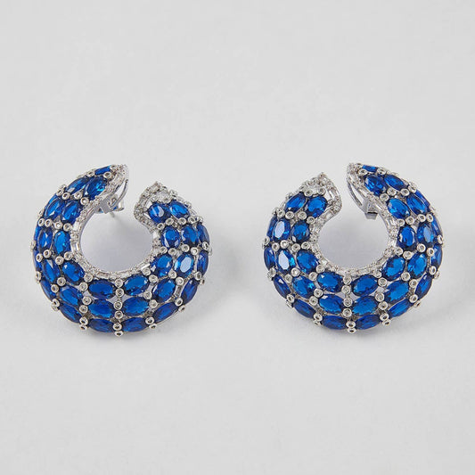 Pair of hoop earrings with blue gemstones on a light gray background