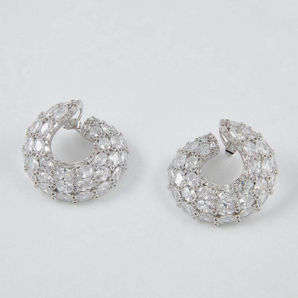Pair of silver hoop earrings with clear stones on a light gray background