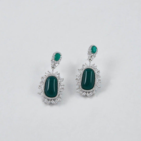 Pair of earrings with green gemstones on a light gray background
