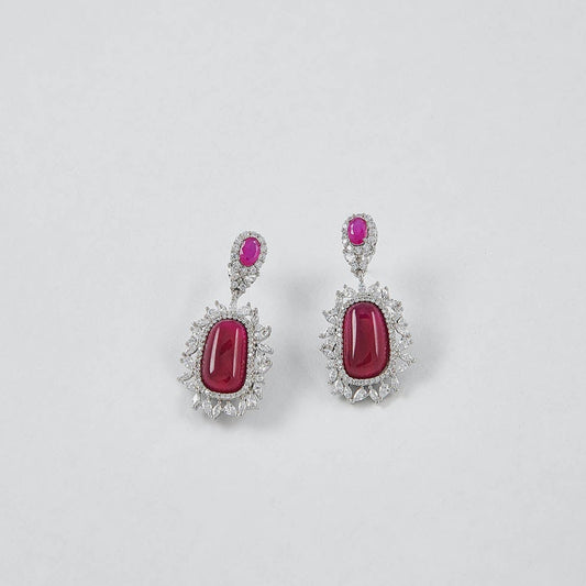 Pair of earrings with red gemstones on a light gray background