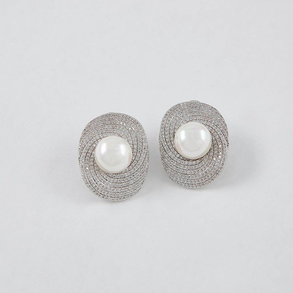 Pair of silver earrings with pearl centers on a light gray background
