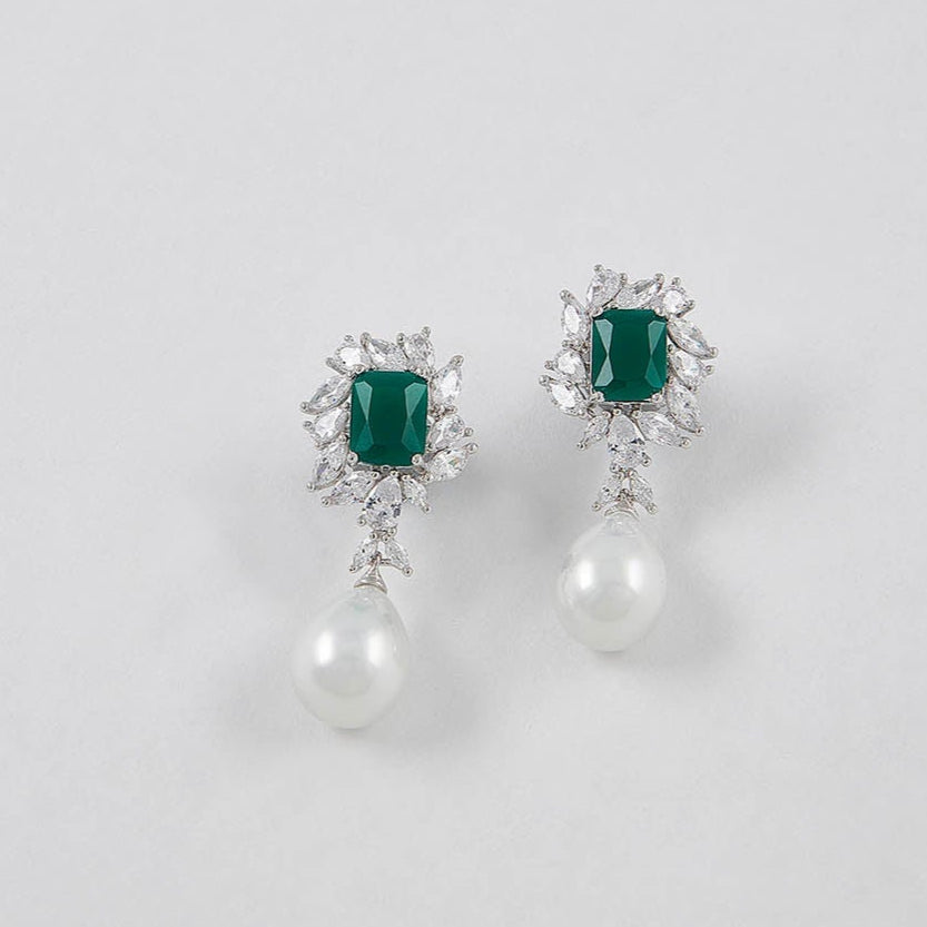 Pair of earrings with emerald green gemstones on a light gray background