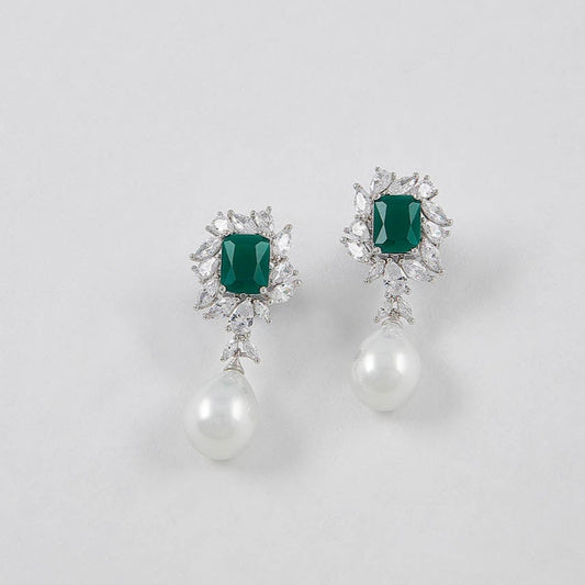 Pair of earrings with emerald green gemstones on a light gray background