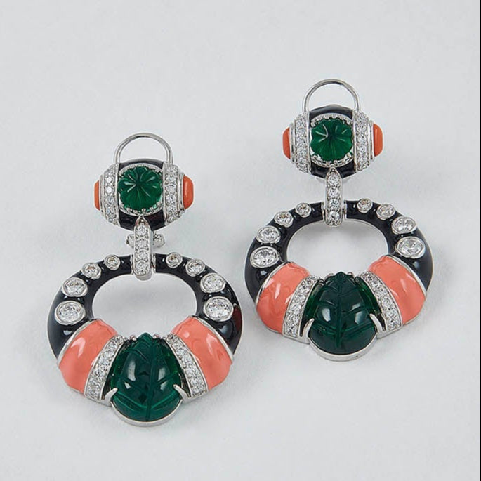 Pair of earrings with green and orange stones on a light gray background