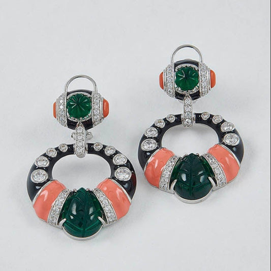 Pair of earrings with green and orange stones on a light gray background