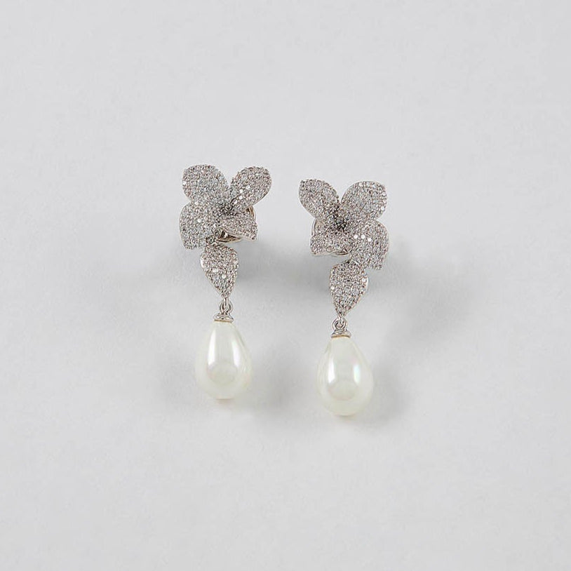 Butterfly-shaped earrings with pearl drops on a light gray background