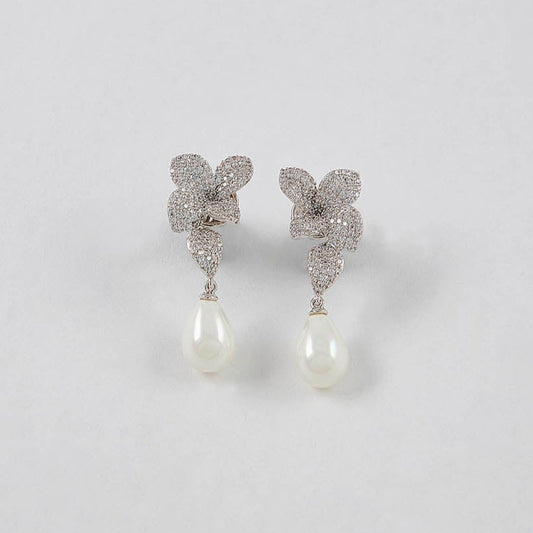 Butterfly-shaped earrings with pearl drops on a light gray background
