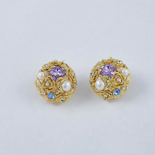 Pair of gold earrings with gemstones on a light gray background