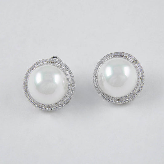 Pair of pearl earrings with silver frames on a light gray background
