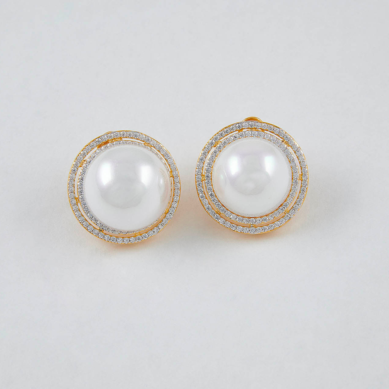 Pair of pearl earrings with gold accents on a light gray background